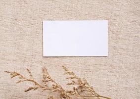 Flat lay of branding identity business name card on brown fabric background with flower, minimal concept for design