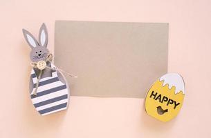 Happy Easter concept with blank card, wooden bunny and colorful easter eggs on yellow background. Top view with copy space photo