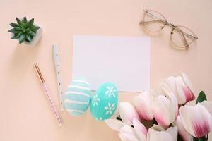 Happy Easter concept with blank card and colorful easter eggs and pink tulips. Top view with copy space photo