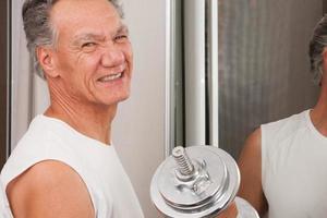 Mature Man 60plus working out with weights at home in front of a mirror doing Bicep Curls photo