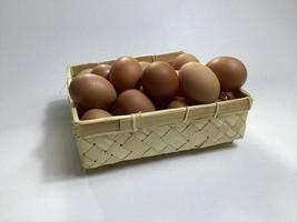 chicken eggs in a bamboo basket on a white background photo