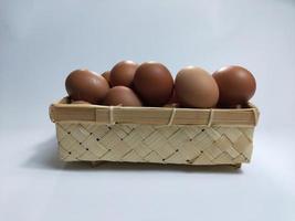 chicken eggs in a bamboo basket on a white background photo