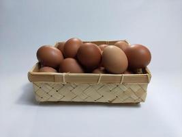 chicken eggs in a bamboo basket on a white background photo