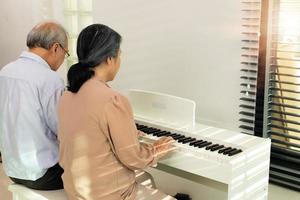 pareja de ancianos mayores tocan música de piano juntos. grupo de dos personas maduras inteligentes asiáticas se jubilan y obtienen un fondo de pensiones. los abuelos expresan sentirse felices por el trato. concepto envejecer juntos, copiar espacio foto
