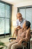 Senior Elderly Couple hold hands together after retirement, Husband wife person take care each other in romantic time with smile happy enjoy. Asian grandparent sit on wheel chair looking, copy space photo