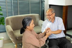 Senior Elderly Couple hold hands together after retirement, Husband wife person take care each other in romantic time with smile happy enjoy. Asian grandparent sit on wheel chair looking, copy space photo