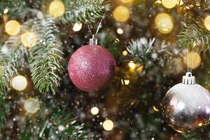 clásico árbol de año nuevo decorado con adornos de adorno rosa y blanco juguete y bola, nieve y luces de guirnalda desenfocadas. diseño de vacaciones clásico moderno. Nochebuena en casa. foto
