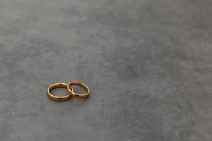 Will you marry me. Two golden wedding rings on concrete stone grey background. Engagement marriage proposal wedding concept. Banner on wedding day with copy space. Wedding day details. photo