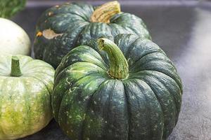 Autumnal Background. Natural autumn fall view pumpkins on dark black stone shale background, October or september wallpaper Change of seasons ripe organic food concept Halloween party Thanksgiving day photo