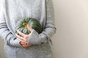 fondo otoñal. mano de mujer irreconocible sosteniendo en las manos calabaza de otoño caída aislada sobre fondo blanco. cambio de estaciones alimentos orgánicos maduros, fiesta de halloween día de acción de gracias. foto