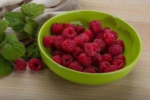 Fresh raspberry in a bowl on wooden background photo