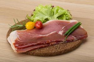 Prosciutto on wooden background photo