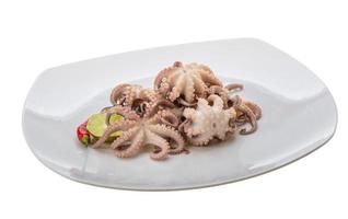 pulpo hervido en el plato y fondo blanco foto