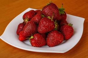 Strawberry on the plate and wooden background photo