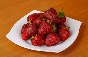 Strawberry on the plate and wooden background photo