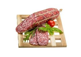 Salami on wooden board and white background photo