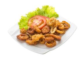 Anillos de calamar fritos en el plato y fondo blanco. foto