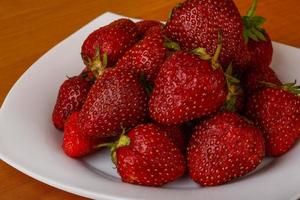 Strawberry on the plate and wooden background photo