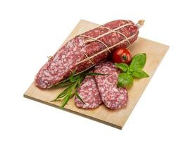 Salami on wooden board and white background photo