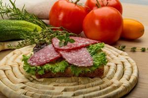 Salami sausages on wooden board and wooden background photo