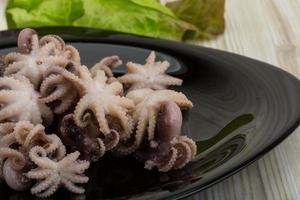 Boiled octopus on the plate and wooden background photo