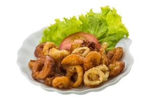 Anillos de calamar fritos en el plato y fondo blanco. foto