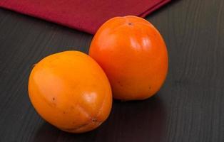 Persimmon on wooden background photo