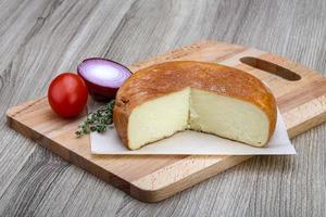 Suluguni cheese on wooden plate and wooden background photo