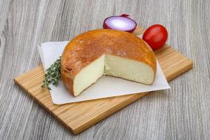 Suluguni cheese on wooden plate and wooden background photo