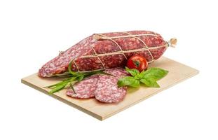 Salami on wooden board and white background photo