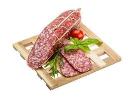 Salami on wooden board and white background photo