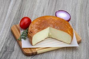 Suluguni cheese on wooden plate and wooden background photo