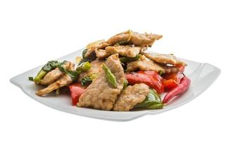 Pork with vegetables on the plate and white background photo