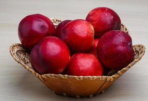 Nectarines in a basket on wooden background photo