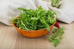 Ruccola in a bowl on wooden background photo