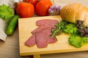 Salami on wooden board and wooden background photo