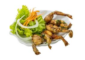 Grilled frog legs on the plate and white background photo