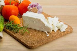 Feta cheese on wooden board and wooden background photo