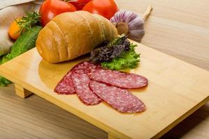 Salami on wooden board and wooden background photo