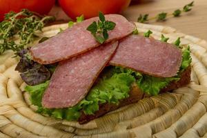 salchichas de salami sobre tablero de madera y fondo de madera foto