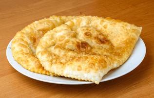 Cheburek on the plate and wooden background photo