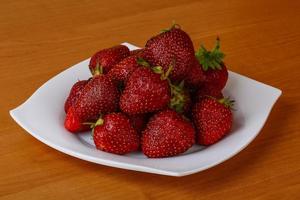 Strawberry on the plate and wooden background photo