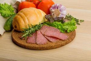 Salami on wooden board and wooden background photo