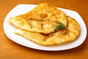 Cheburek on the plate and wooden background photo