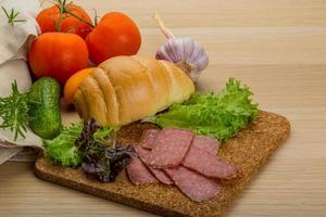 salchichas de salami sobre tablero de madera y fondo de madera foto