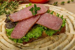 Salami sausages on wooden board and wooden background photo