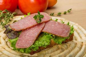 salchichas de salami sobre tablero de madera y fondo de madera foto