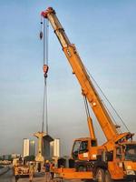 West Java, Indonesia on July 2022. A yellow crane is lifting the segmental precast girder. photo