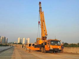 West Java, Indonesia on July 2022. A yellow crane is lifting the segmental precast girder. photo
