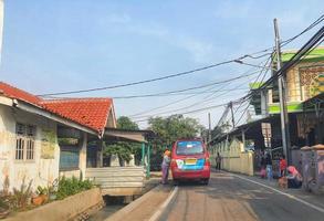 West Java, Indonesia on July 2022.A red public transport car is stopping in an alley to pick up passengers. photo